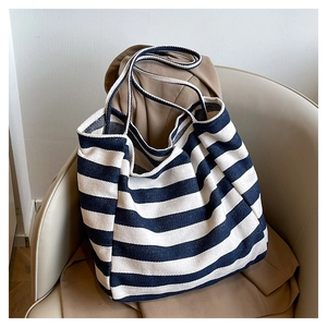 Detail of blue and white striped canvas tote bag showing twill texture on a beige sofa