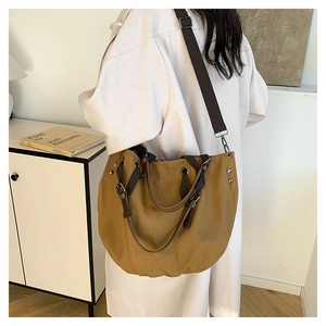 Detail of mustard canvas tote bag showing metal rivets and durable crossbody strap