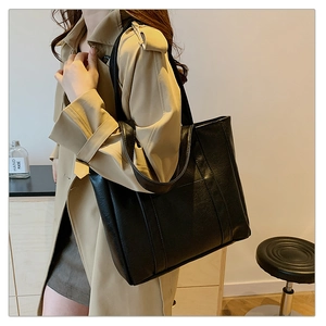 Detailed view of black leather tote bag with elegant texture and sturdy shoulder straps