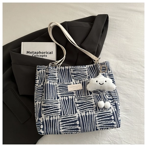 Detail of canvas tote bag with blue geometric pattern and cloud charm on fabric background