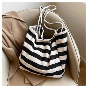 Detail view of a black and white striped canvas tote bag with white rope handles on a chair
