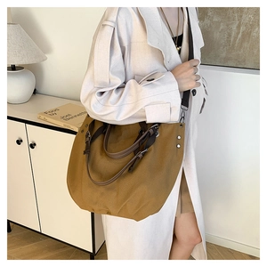 Detail of vintage brown canvas tote bag with adjustable straps and metal rivet accents