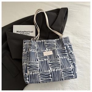 Detail of blue and white abstract line pattern tote bag with white leather strap on suit