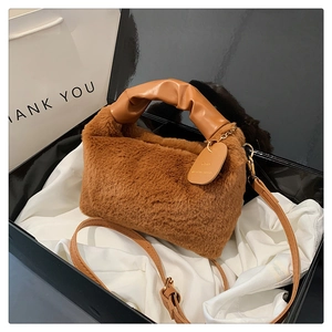 Detailed macro of a brown plush handbag featuring adjustable leather straps and soft texture
