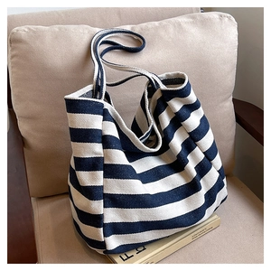 Close-up of navy and cream striped canvas tote bag resting on a beige fabric chair