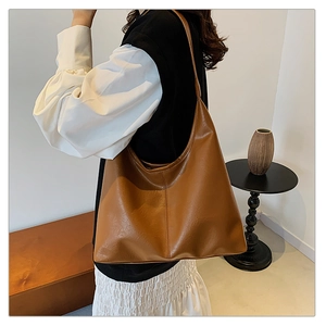 Brown vintage leather hobo tote bag shown on shoulder with minimalist styling