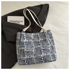 Detail of canvas tote bag featuring blue geometric patterns and dual white shoulder straps