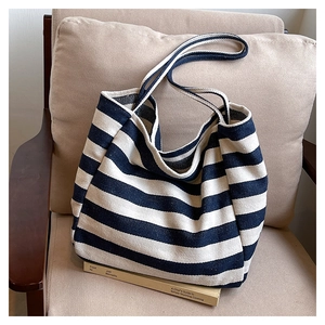 Close-up of striped canvas tote bag texture on armchair with book prop decoration