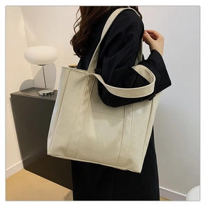 Large cream tote bag in lychee texture faux leather shown on shoulder for daily commute