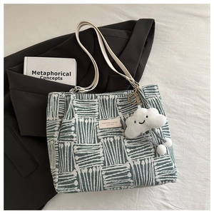 Detail of green and white woven tote bag texture with cloud charm and fashion label