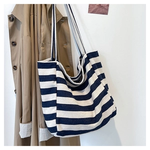 Detailed texture of blue and white striped canvas tote bag on a stylish trench coat