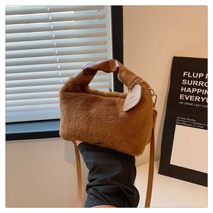 Detail of plush brown faux fur bag with leather handle and heart-shaped 'YOU' charm