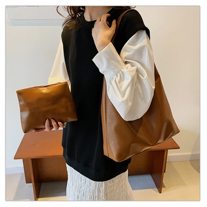Brown tote bag and matching clutch set shown with leather texture on a wooden bench