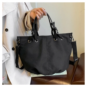 Detail of black canvas tote bag with adjustable shoulder strap and silver metal eyelets
