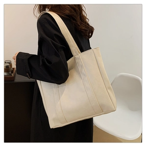 Detail of creamy white tote bag featuring premium lychee grain texture and front pocket