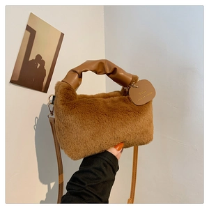Detail of soft brown faux fur handbag with leather handle and decorative 'You' tag