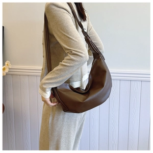Brown hobo bag shown from a side view on model highlighting the vintage minimalist design
