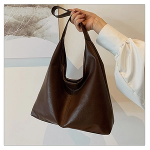 Detail of dark brown leather hobo bag with vintage texture and central stitching detail