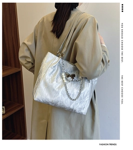 Detail of silver wrinkled tote bag featuring metal chains and elegant pearl ornaments