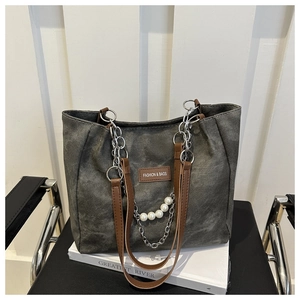 Detail of grey canvas tote with brown leather handles, silver chains and pearl charms