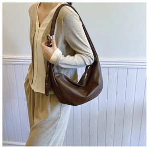 Detail view of deep brown faux leather crescent bag with adjustable buckle strap and silver hardware