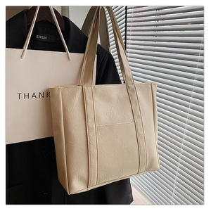 Close-up of cream white tote bag featuring retro pleated texture and convenient front pocket