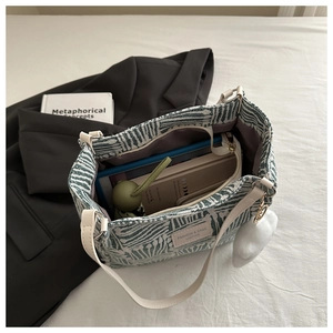 Spacious interior of green striped tote showing tablet, umbrella, and notebook storage