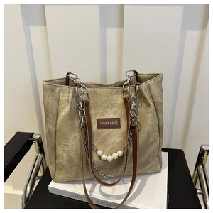 Detail of khaki canvas tote with brown leather straps, silver chain and pearl accents