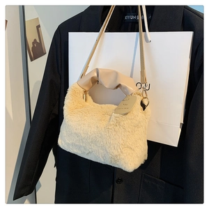 Detail of plush beige handbag featuring ruched leather handle and decorative metal tag