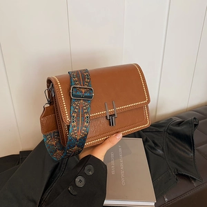 Vintage brown leather crossbody bag with geometric print strap and metal buckle closure