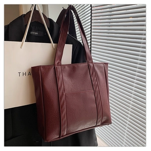 Burgundy faux leather tote bag detail with long handles and textured surface