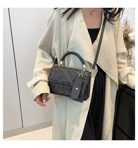Detail of black quilted shoulder bag with FASHION lettering and small card holder