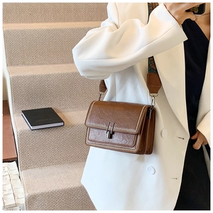 Detailed view of brown retro shoulder bag featuring silver clasp and studded edge accents