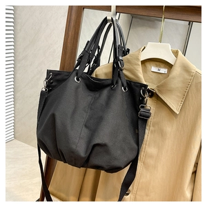 Detail of black canvas tote bag with leather handles and wide adjustable shoulder strap