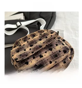 Close-up of khaki checkered crossbody bag with black heart flocking and white strap
