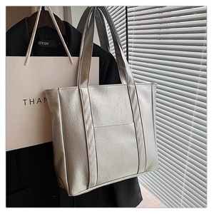 Detail of silver metallic tote bag featuring fine leather texture and front pocket design