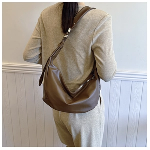 Detail of dark brown hobo shoulder bag with matte leather texture and adjustable strap