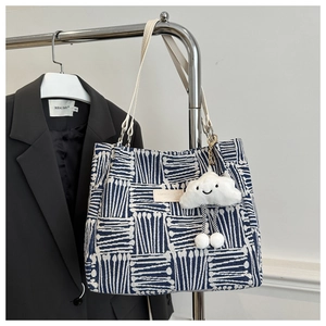 Detailed close-up of blue canvas tote bag featuring geometric patterns and cloud charm