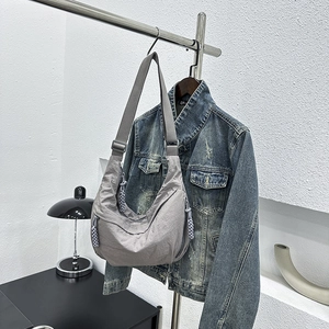 Grey crescent nylon bag with rope charm hanging on a hanger against white wall