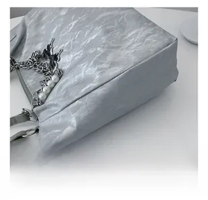 Detail of silver tote bag featuring marble texture fabric and butterfly chain pendant