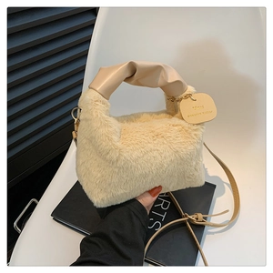 Detail of beige faux fur handbag featuring leather handle and gold hardware link