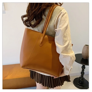 Brown leather tote bag worn by a model in a minimalist and elegant home setting