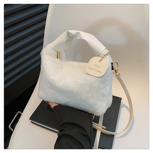 Close-up of white plush handbag featuring faux fur texture and a gold quote charm