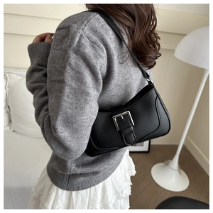 Detail of a black leather underarm bag featuring a retro silver square buckle and strap