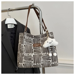 Detail of canvas tote bag with geometric pattern and cute plush cloud charm on a hanger