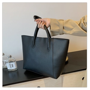 Close-up of black matte tote bag featuring vertical stitching and adjustable shoulder strap