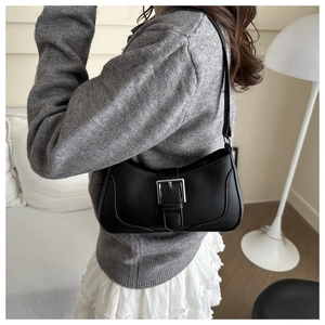 Detail of a chic black underarm bag with a bold silver buckle for a retro urban look