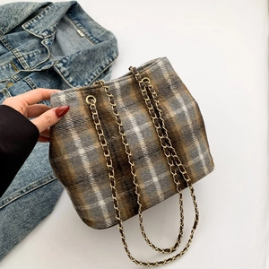 Retro brown checkered drawstring bucket bag with gold chain strap over denim jacket