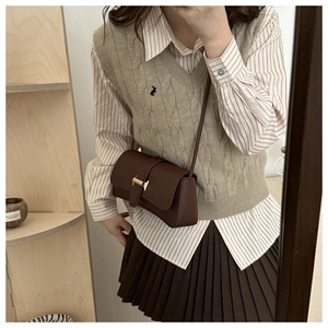 Detail of vintage dark brown crossbody bag with gold metal buckle on a female model