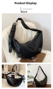 Detail of black hobo bag showing wide strap with silver metal eyelets and belt buckle